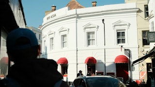 Person walking down the street in Europe and looking at a white hotel