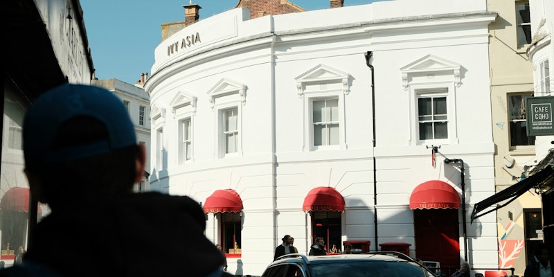 Person walking down the street in Europe and looking at a white hotel