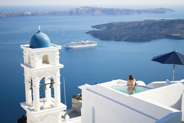 Person staring out at the bay in a hotel pool in Greece