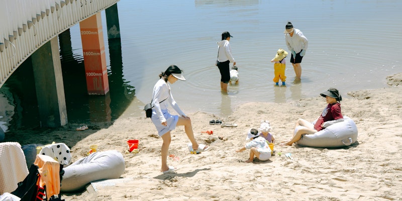 People relaxing on a sandy beach by the water.