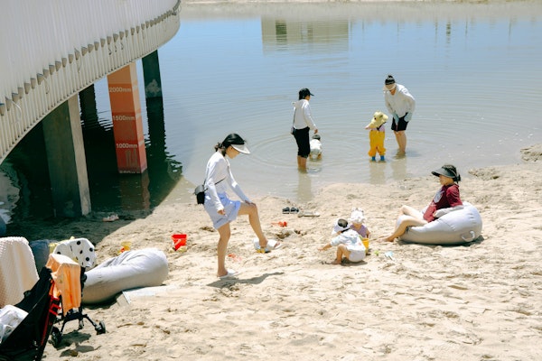 People relaxing on a sandy beach by the water.