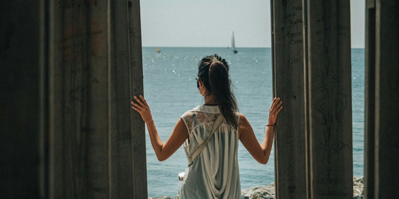 woman in white dress standing on beach during daytime