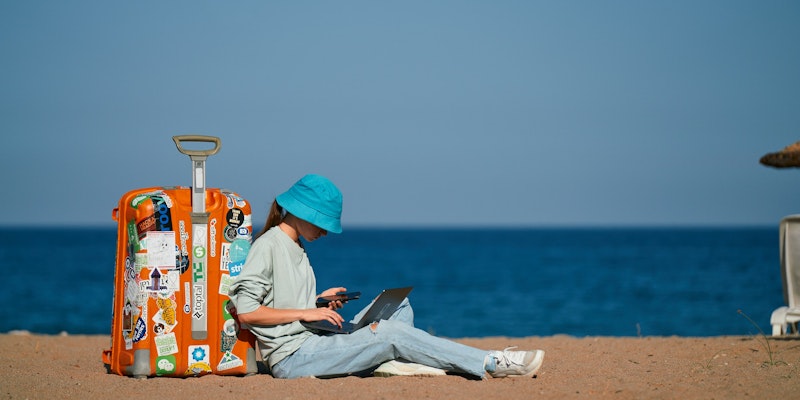 a person sitting on the beach with a suitcase