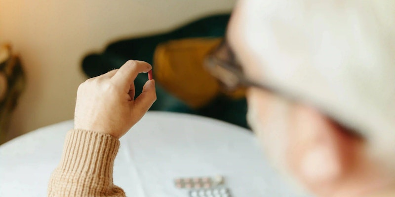 Imagem de uma pessoa segurando um comprimido de albendazol.