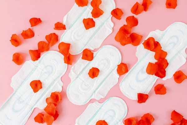 imagem de absorventes e petalas de rosa, simulando menstruação.