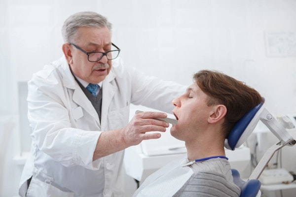 Imagem de um dentista diagnosticando DTM.