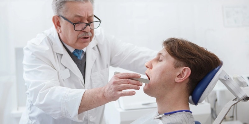 Imagem de um dentista diagnosticando DTM.
