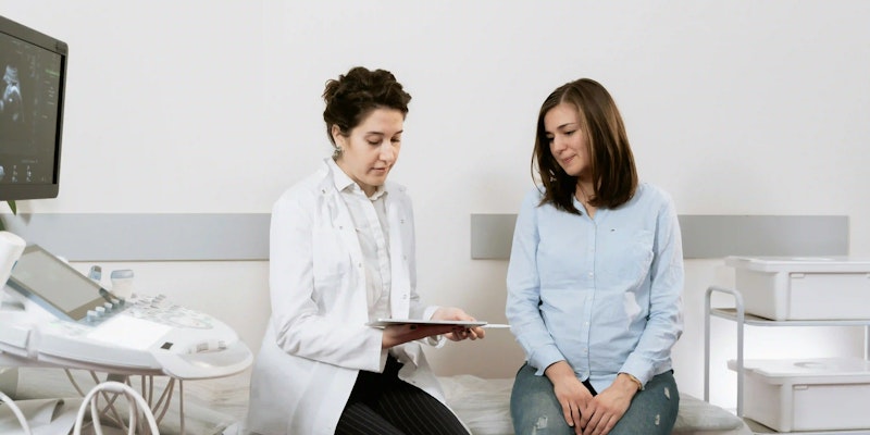 Imagem de uma paciente e uma médica conversando em um consultório sobre doenças autoimunes.