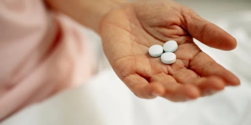 Imagem de uma pessoa com comprimidos de Atrovet em suas mãos.