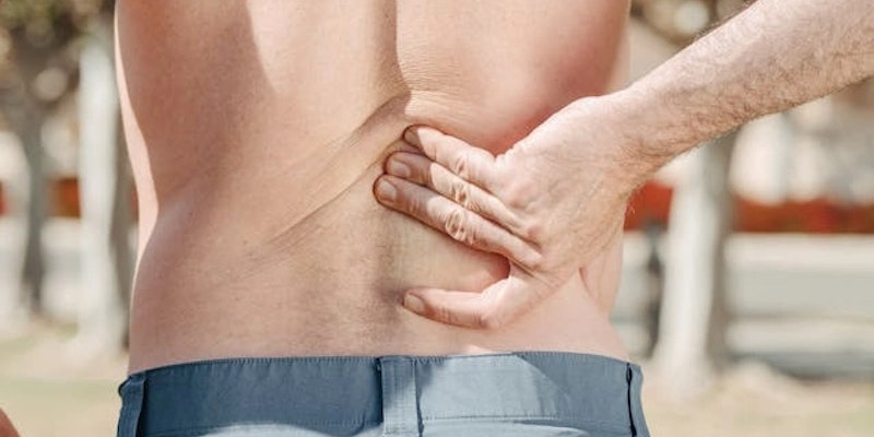 Imagem de homem com insuficiência renal, com as mãos apoiadas em suas costas.