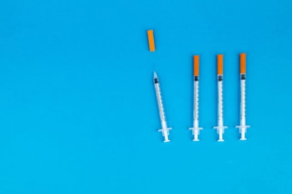 Seringas sobre fundo azul, representando o alerta sobre caneta emagrecedora contrabandeada e os riscos do uso de medicamentos injetáveis sem procedência.