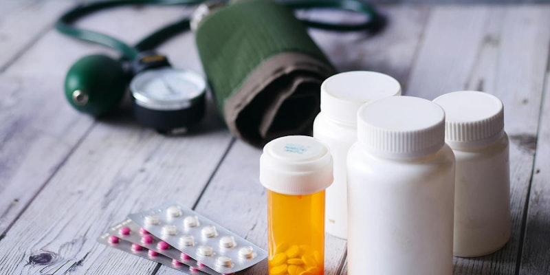 Frascos de medicamentos e aparelho de pressão arterial sobre mesa, ilustrando o uso de Indapamida no controle da pressão alta e retenção de líquidos.