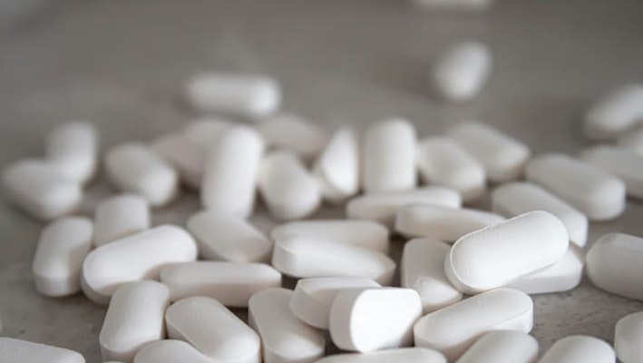 Comprimidos de paracetamol espalhados sobre uma superfície para aliviar dores e reduzir a febre.