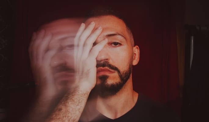 Homem com expressão séria e efeito visual de duplicação do rosto, com sintomas de transtornos mentais como esquizofrenia e do transtorno bipolar tratados com olanzapina.
