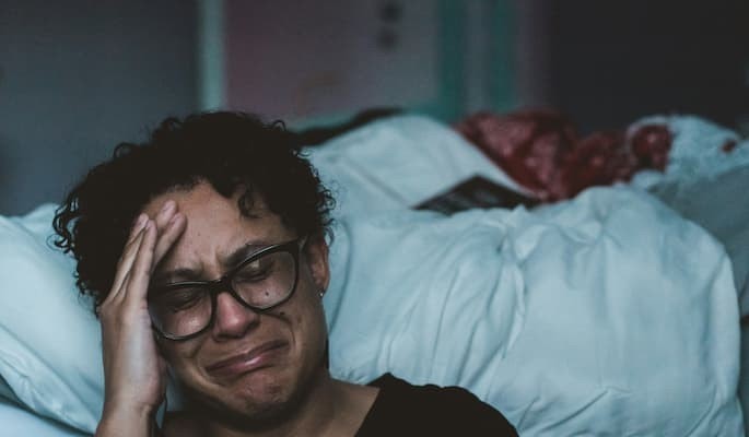 Pessoa sentada ao lado da cama com expressão de tristeza e sofrimento emocional com depressão e ansiedade tratadas com duloxetina.