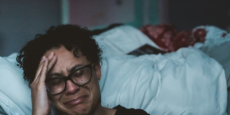 Pessoa sentada ao lado da cama com expressão de tristeza e sofrimento emocional com depressão e ansiedade tratadas com duloxetina.