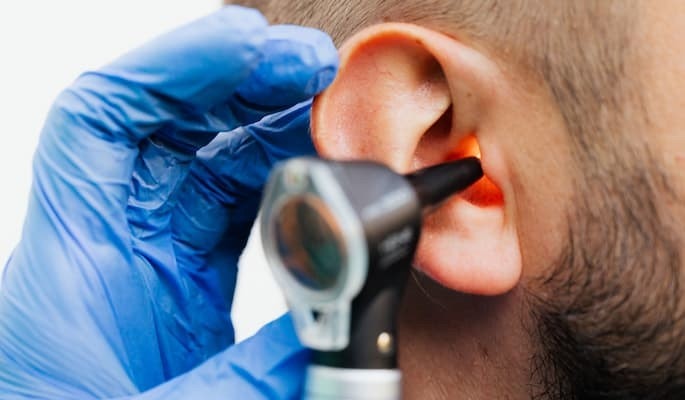 Profissional de saúde examinando o ouvido de um paciente com um otoscópio com diagnóstico e tratamento de infecções e inflamações do ouvido para o uso de Otociriax.