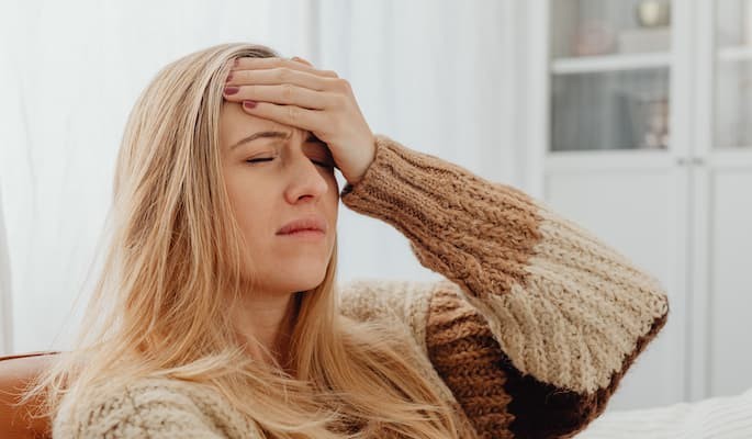 para-que-serve-cloridrato-naratriptana (2) Mulher com a mão na testa e expressão de desconforto devido a uma forte dor de cabeça com sintomas de enxaqueca.