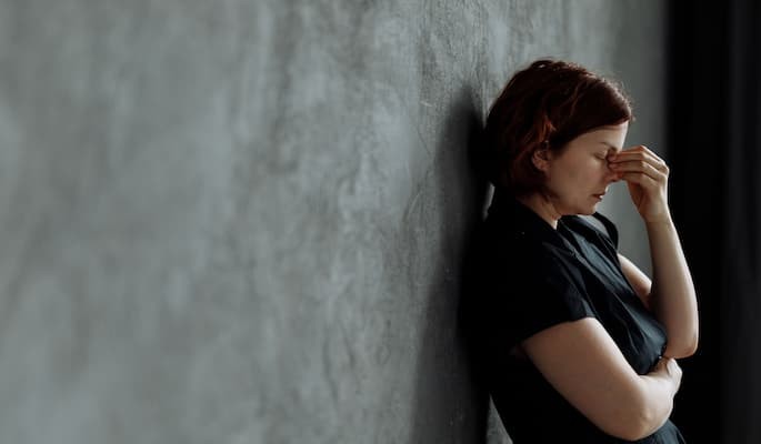 oxalato-escitalopram-para-que-serve (2) Mulher triste encostada em parede cinza com ansiedade.