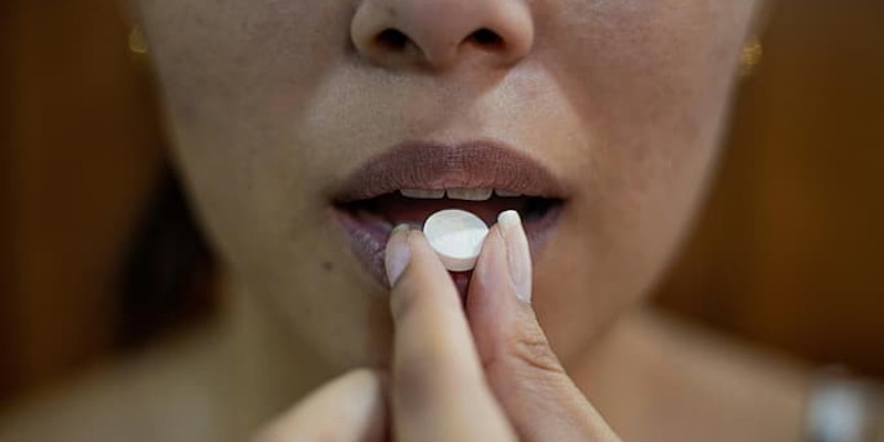 Pessoa levando um comprimido de doxiciclina à boca para ingestão.
