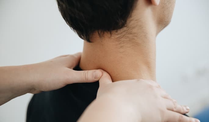 Pessoa recebendo massagem na região do pescoço e dos ombros para aliviar tensão muscular com o uso do remédio Tandrilax em apoio.