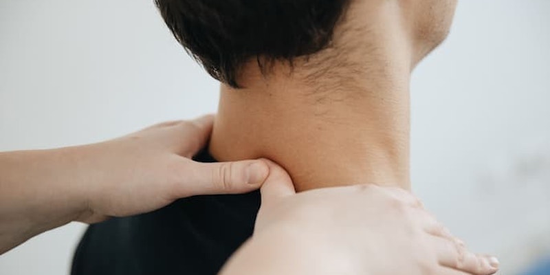 Pessoa recebendo massagem na região do pescoço e dos ombros para aliviar tensão muscular com o uso do remédio Tandrilax em apoio.