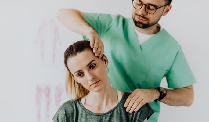 Profissional de saúde realizando mobilização da coluna cervical em paciente para aliviar dor e tensão muscular.