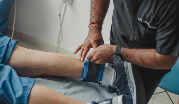 infralax-para-que-serve (2) Profissional de saúde ajustando uma órtese na perna de um paciente durante atendimento fisioterapêutico para tratamento de dores musculares e a reabilitação.
