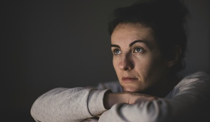 Pessoa sentada com os braços apoiados nos joelhos e olhar distante com sofrimento emocional associados ao transtorno obsessivo-compulsivo (TOC).