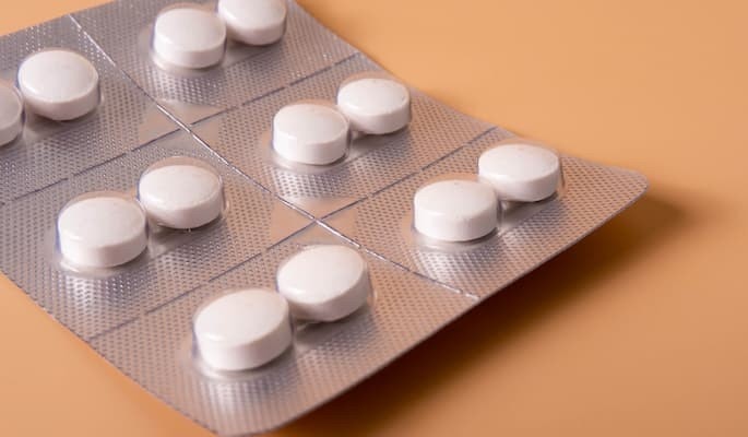 Comprimidos de azitromicina em cartelas sobre uma superfície laranja.
