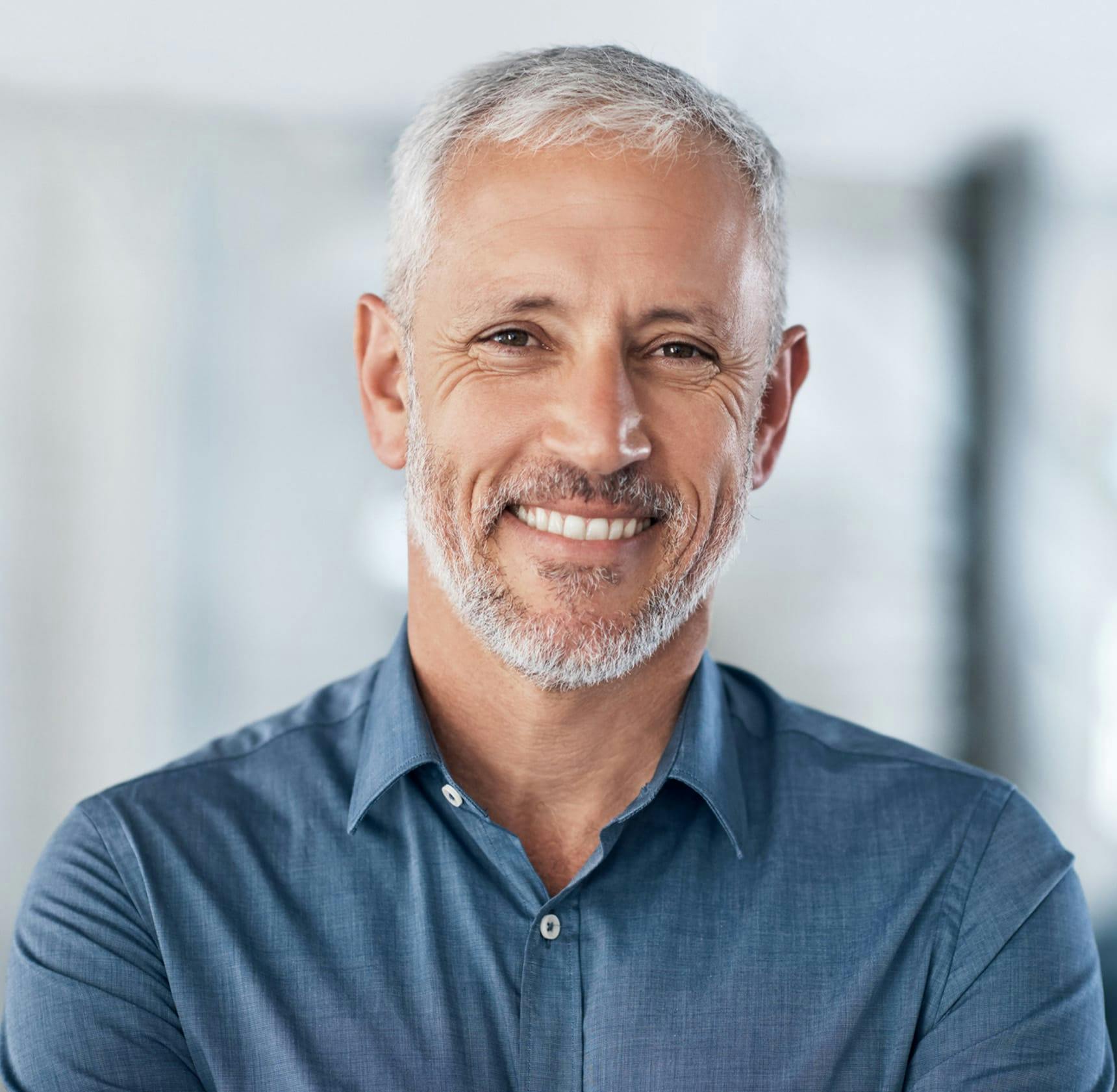 older man smiling while wearing blue shirt