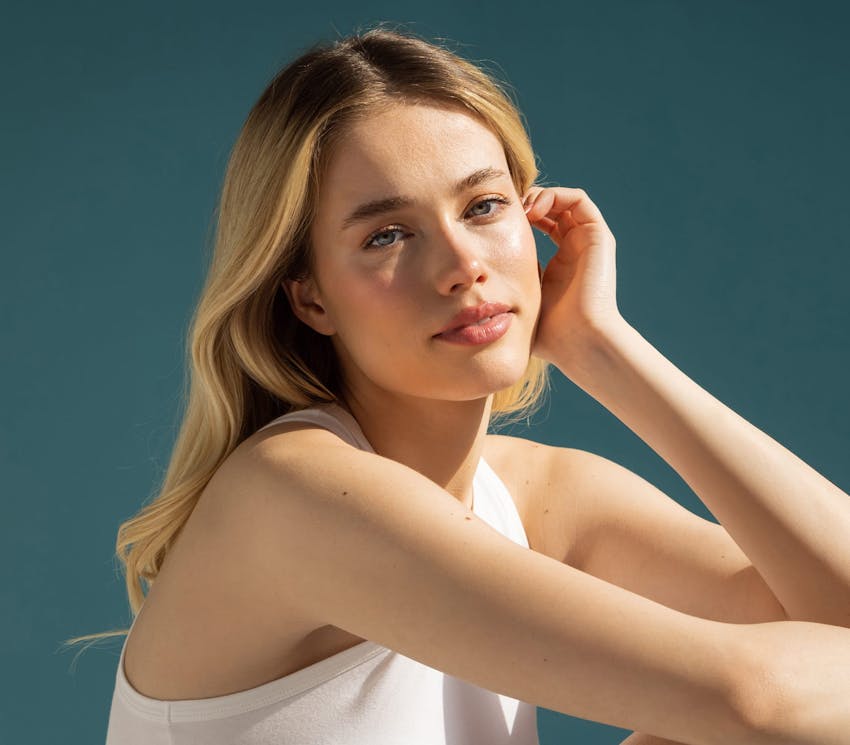 woman moving her hair behind her ear with the sunlight hitting her face