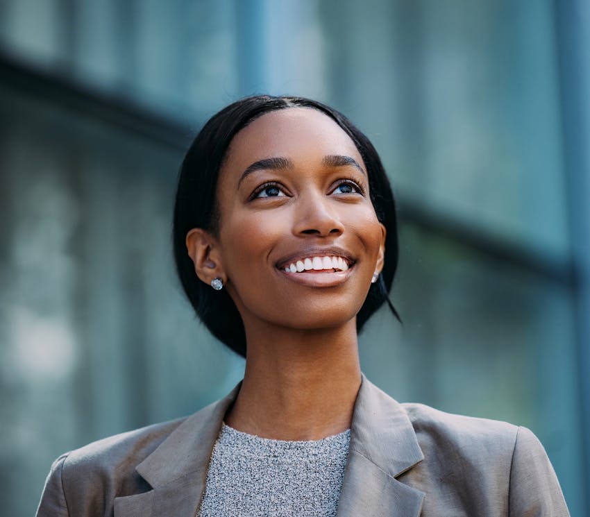 african american woman smiling and is outsite in front of building