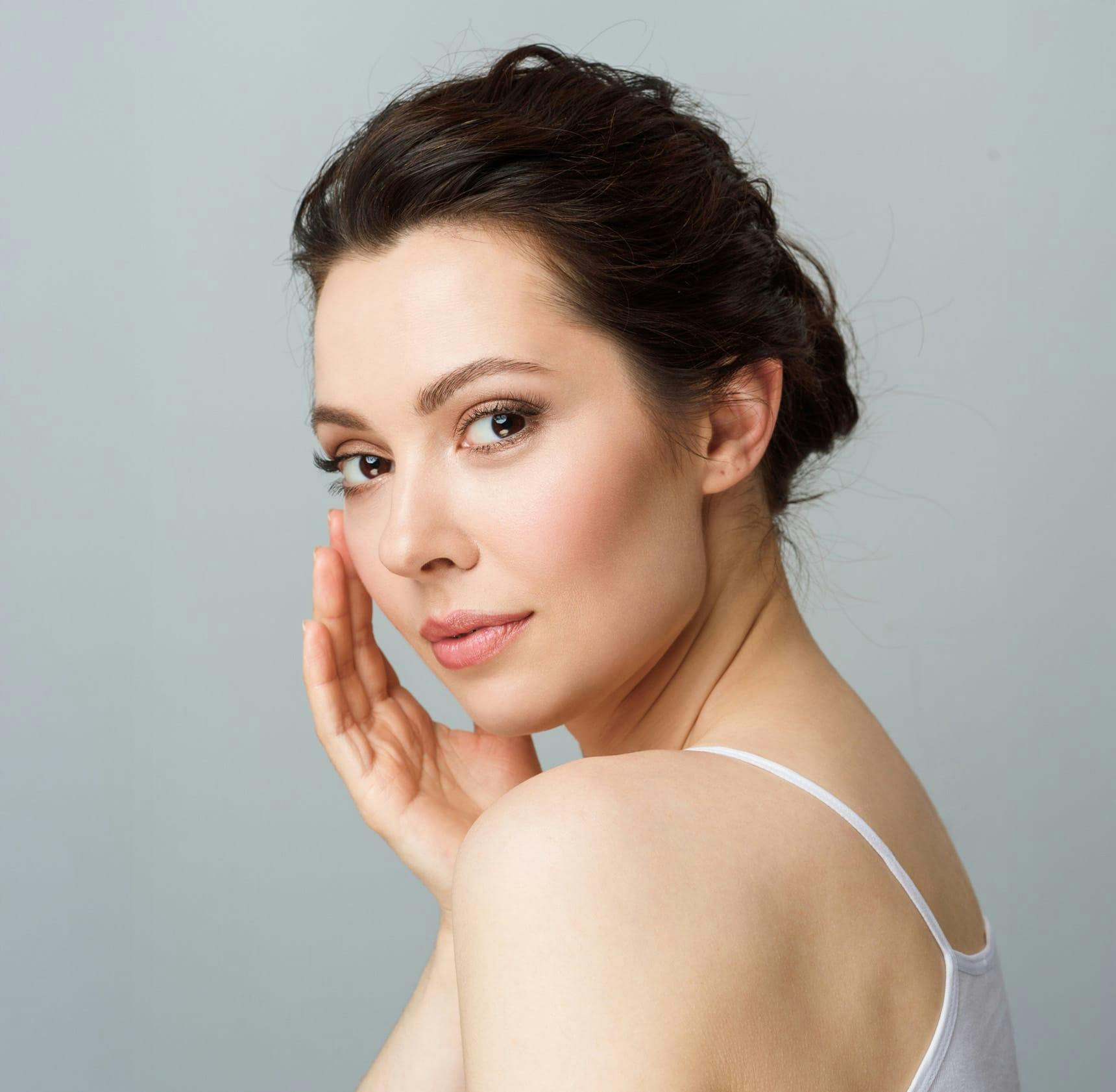 woman looking over her shoulder touching her cheek