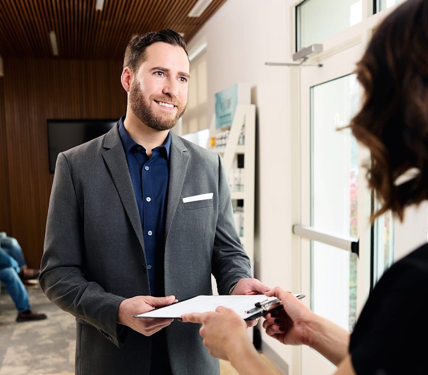 male client getting handed a form to fill out