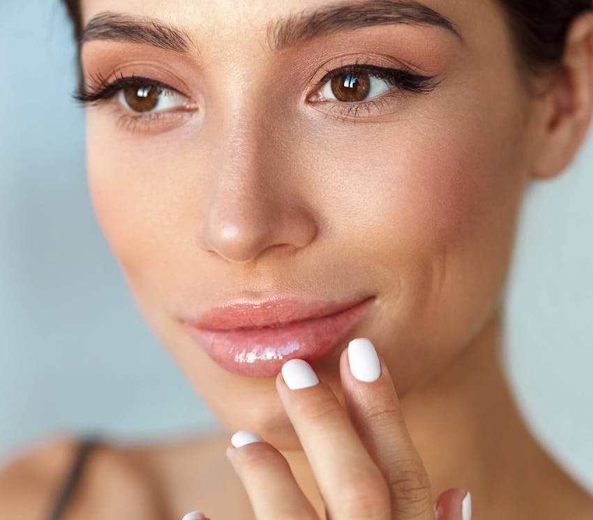close up on woman's face while she touches her bottom lip