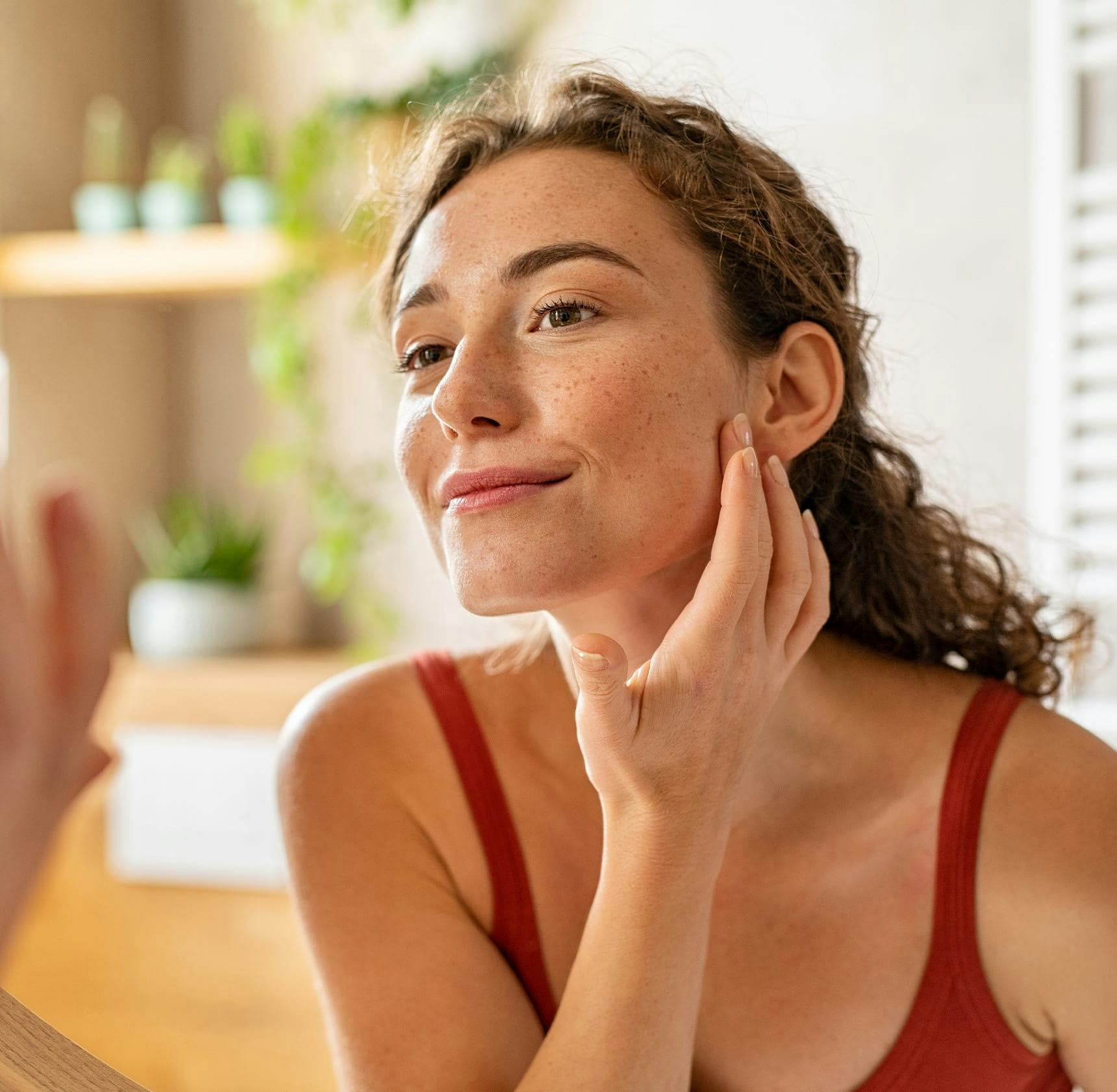 woman looking into a mirror and touching her face
