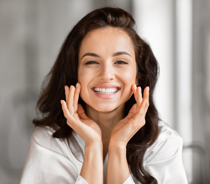 woman smiling with her hands touching both of her cheeks