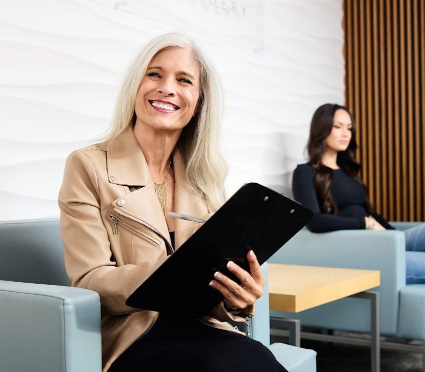 woman sitting in waiting room filling out form on clipboard
