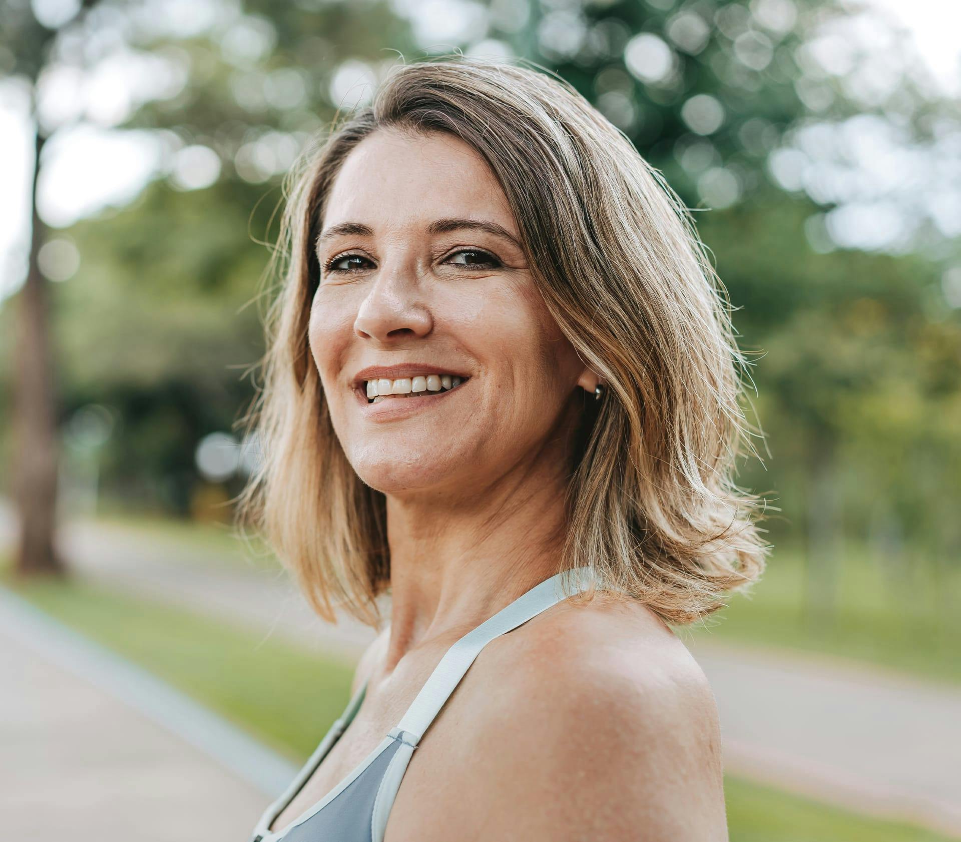 woman outside facing to the side and smiling