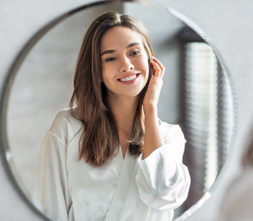 woman smiling and looking in wall mirror