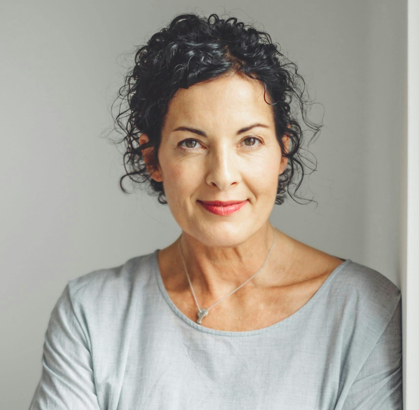 woman with curly hair in grey long-sleeve shirt