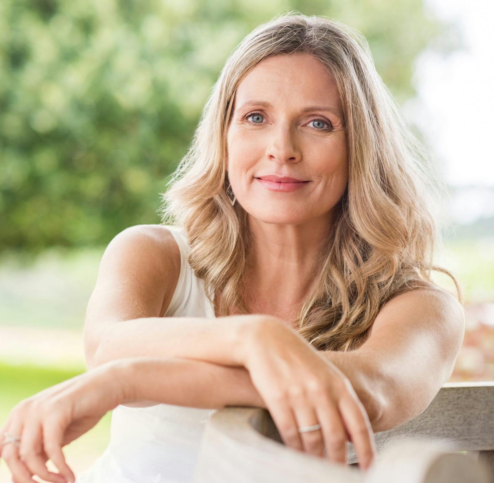 woman outside on picnic table with her arms out in front of her