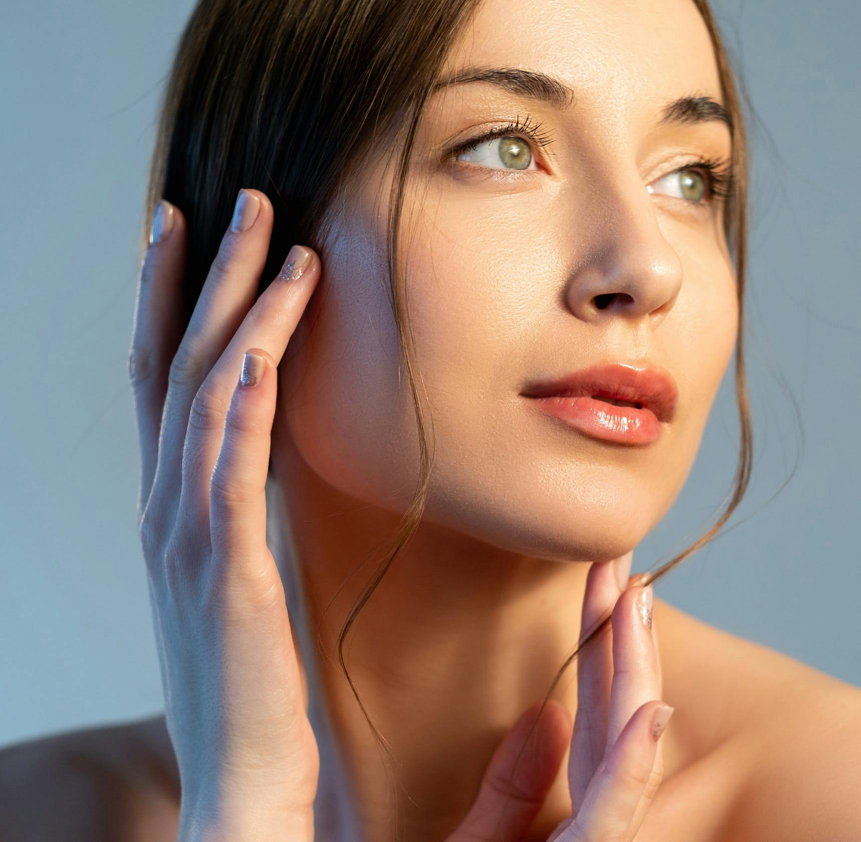 woman with green eyes touching her face and chin