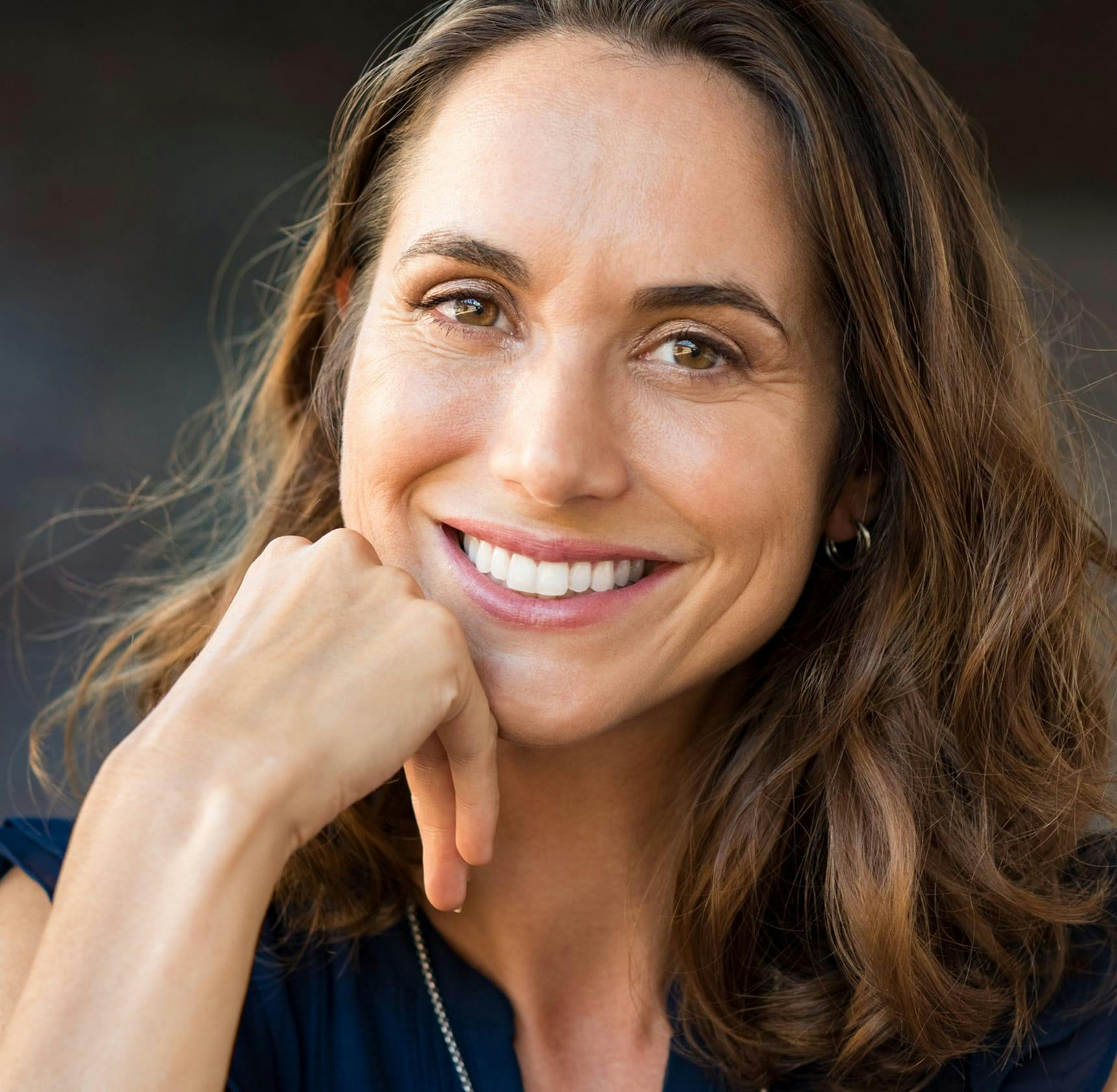 woman smiling with her hand next to her chin