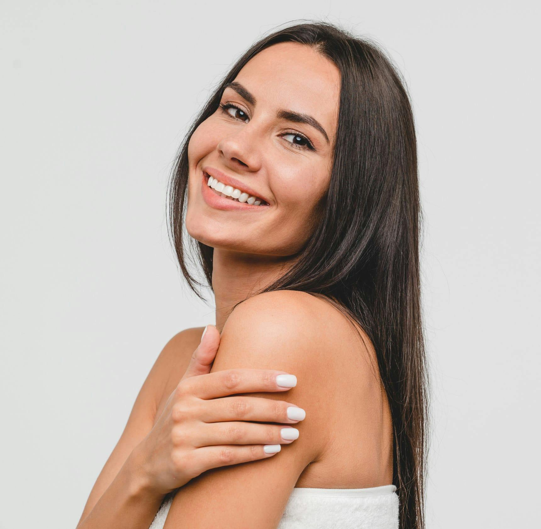 woman smiling and tilting her head back with her hand on her shoulder