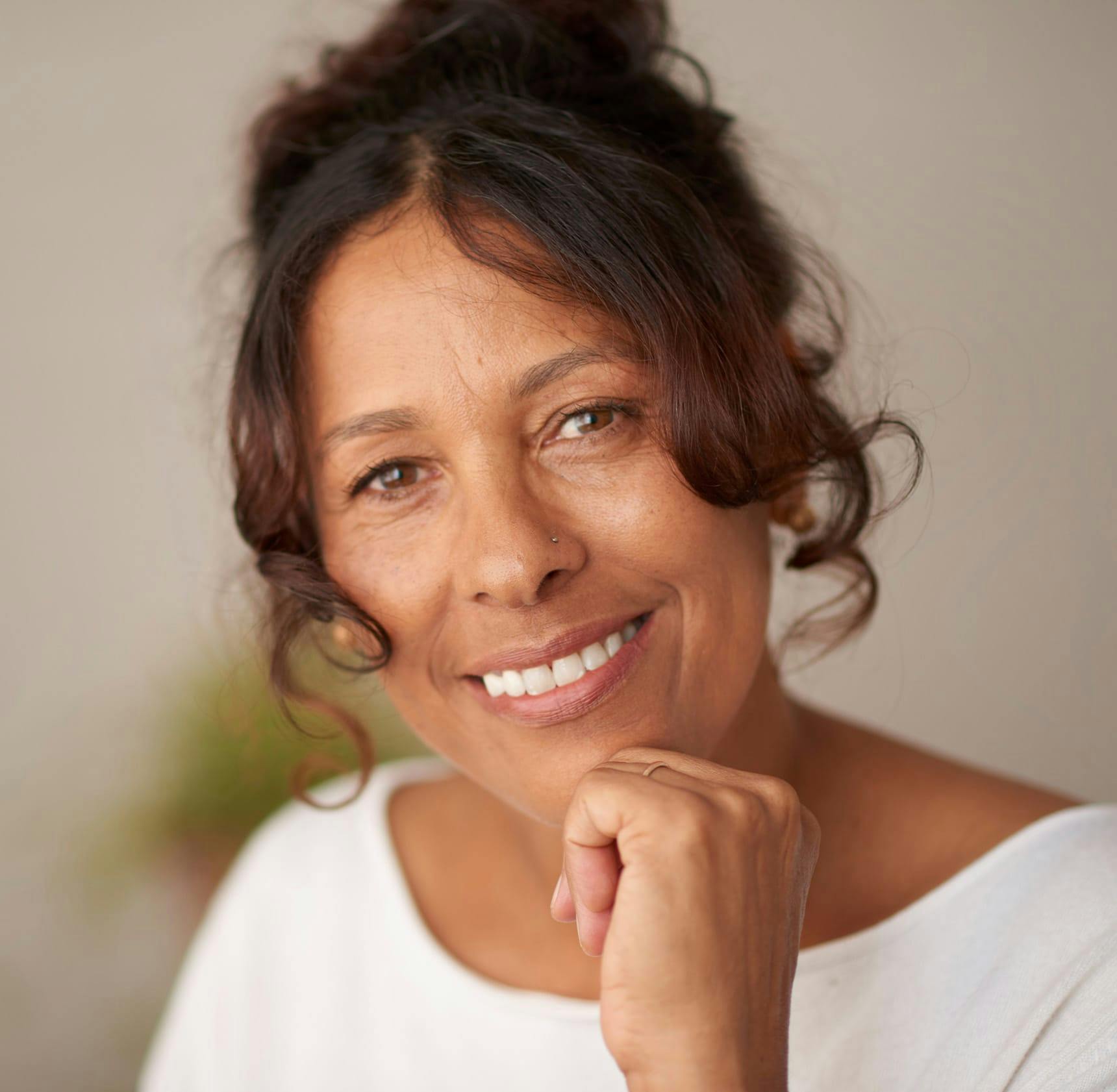 older woman smiling with her hand touching her chin