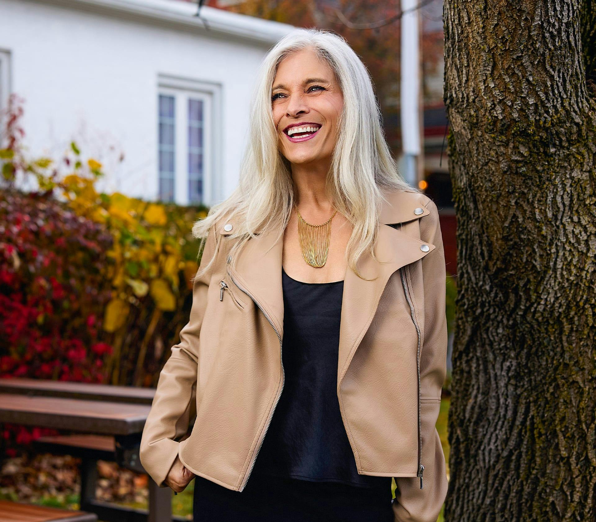female client leaning against a tree outside