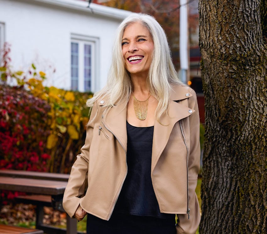 female client leaning against a tree outside
