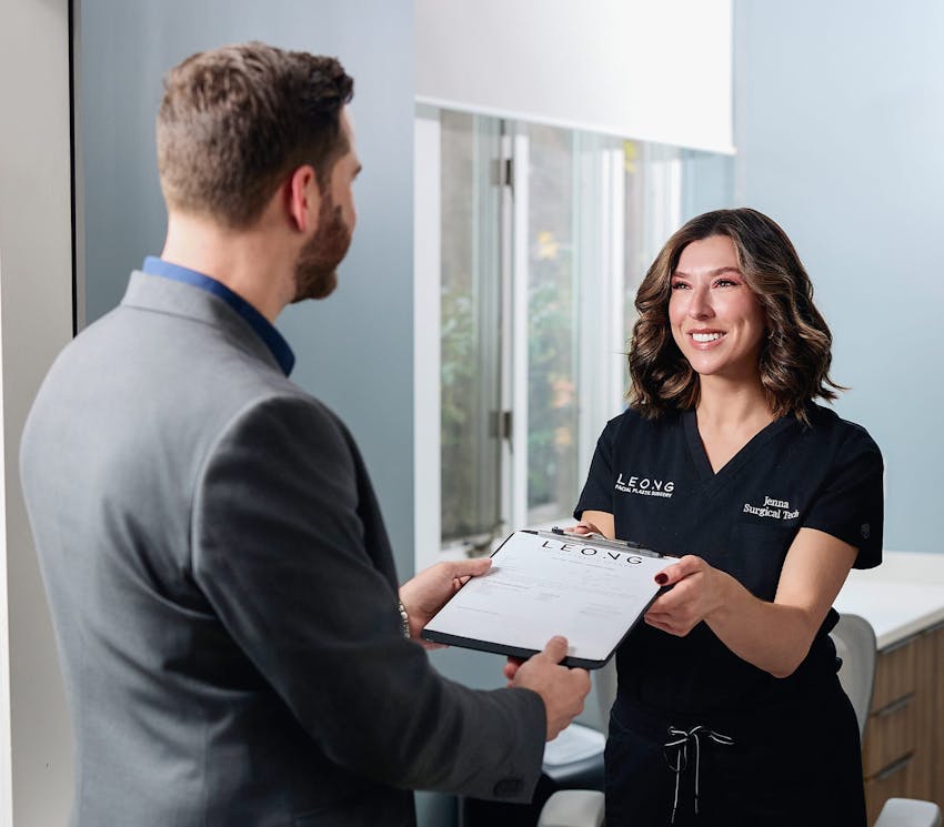 receptionist handing a clipboard to a male client